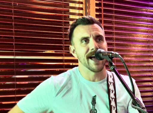 Matt Sofranko, dark-haired, performing guitar and singing